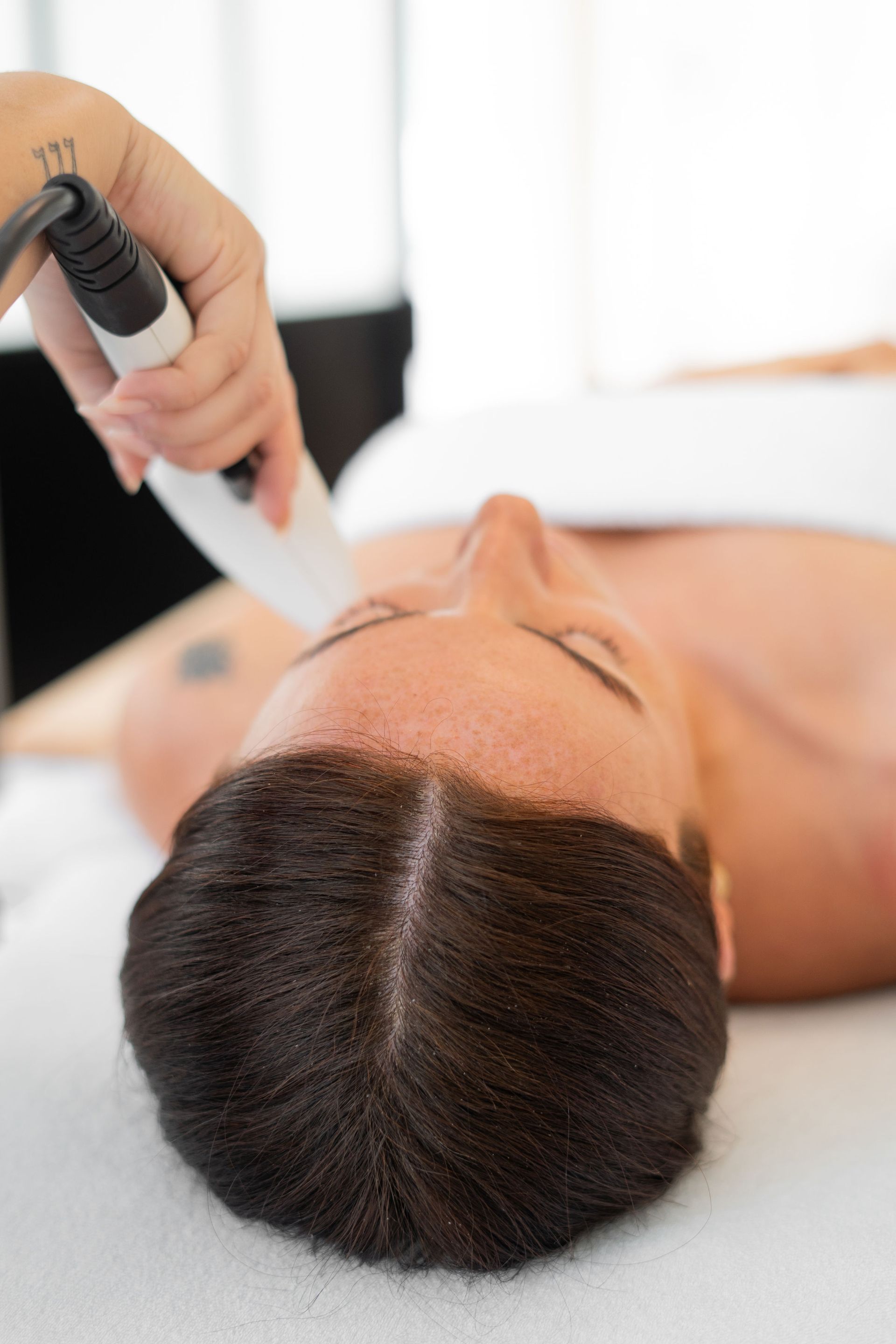 Soin du visage effectué à l’aide d’un appareil portatif sur une femme allongée sur une table de soin en spa