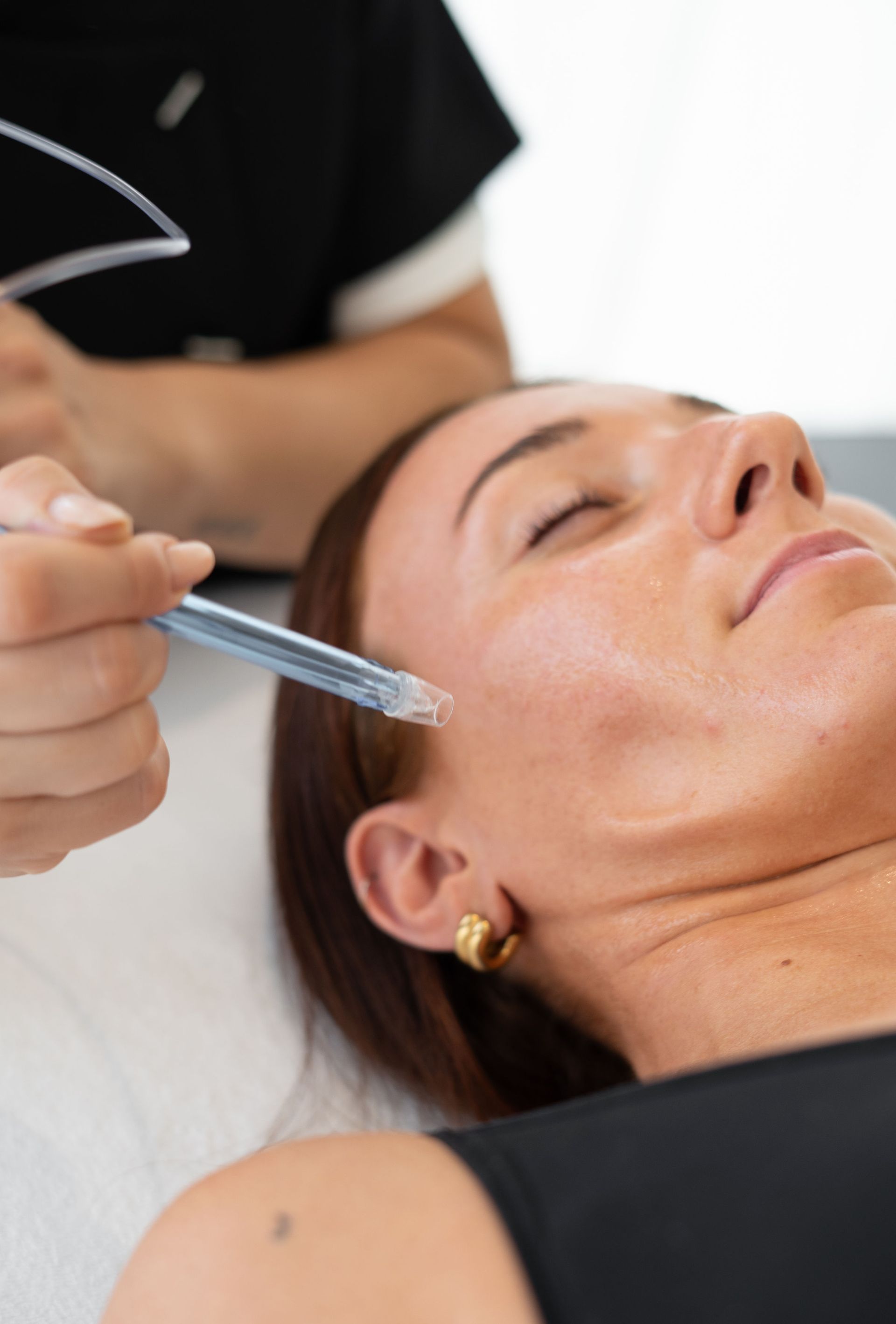 Une praticienne en médecine esthétique injecte un produit dans le visage d’une cliente allongée à l’aide d’une seringue