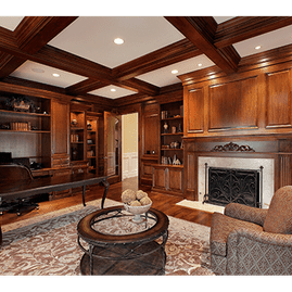 Elegante sala de estar con paneles de madera, techo artesonado, chimenea, muebles empotrados y alfombra estampada.