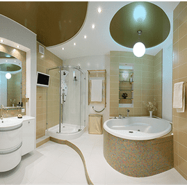 Baño moderno de color beige con bañera, ducha de cristal, lavabo, inodoro y luces de techo redondas.