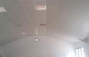 Habitación blanca vacía con techo curvo, reloj de pared redondo y ventanas luminosas a la derecha.