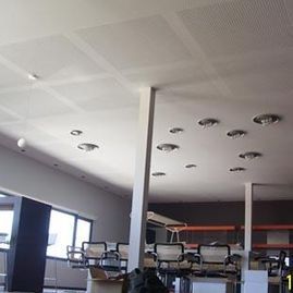 Interior de oficina moderno con escritorios, ventanas y luces empotradas en el techo.