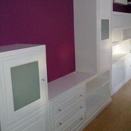 Estanterías y armarios empotrados blancos sobre una pared magenta en una habitación moderna.