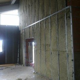 Interior en construcción con aislamiento de paredes a la vista y estructura metálica.