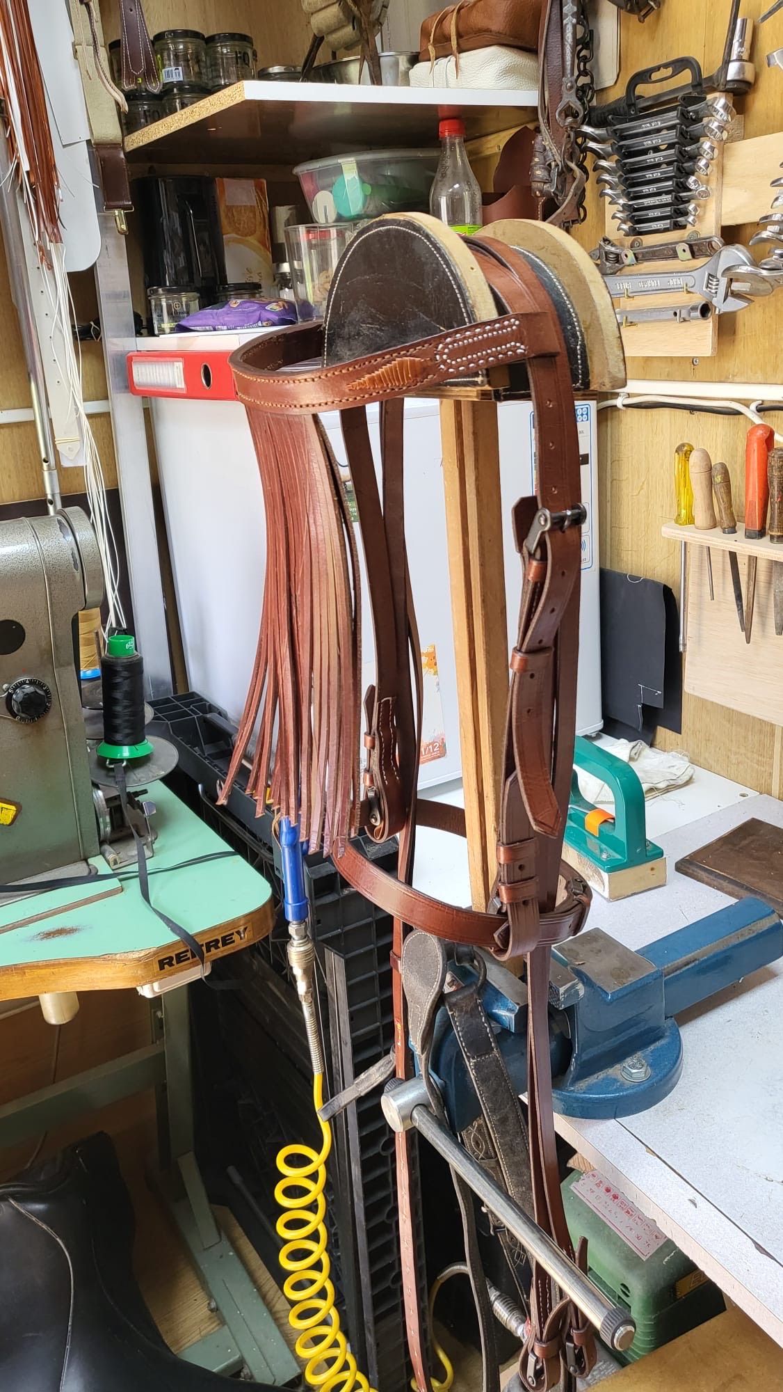 Armazón metálico oxidado con correas y herramientas colgando en un taller desordenado