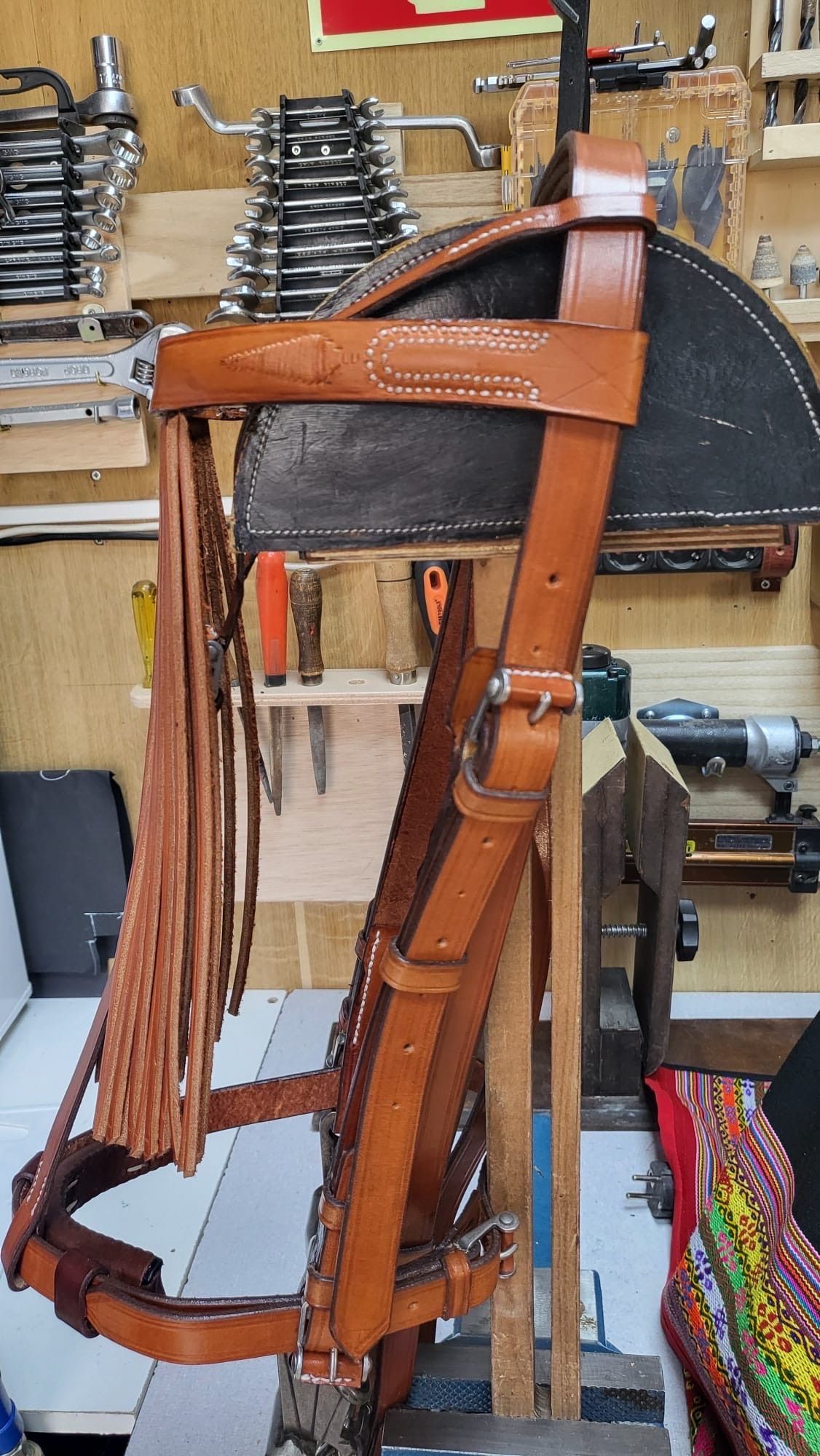 Brida de cuero marrón para caballo con borlas largas colgando en el escaparate de una tienda de artículos ecuestres