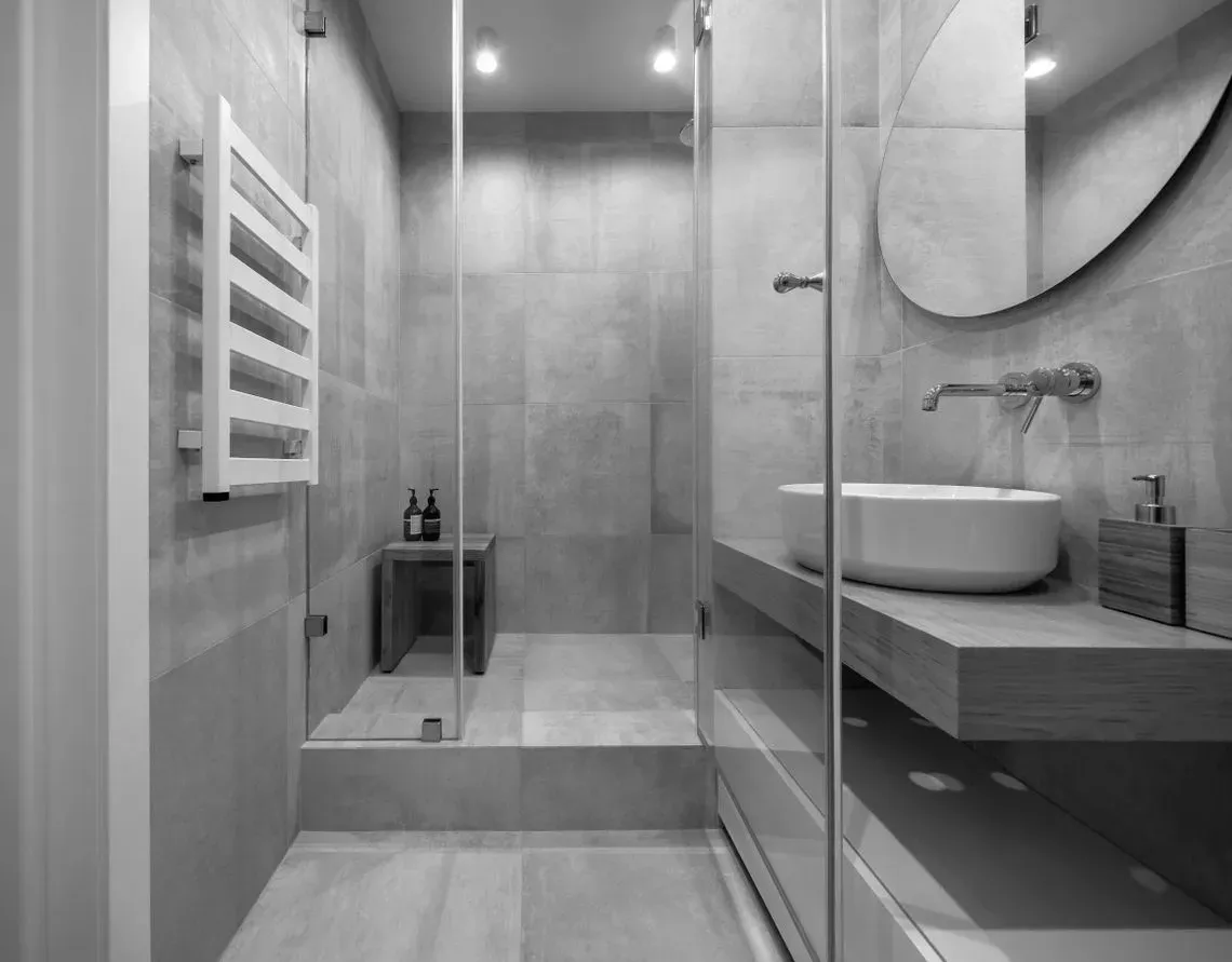 Una fotografía en blanco y negro de un baño con lavabo y ducha.