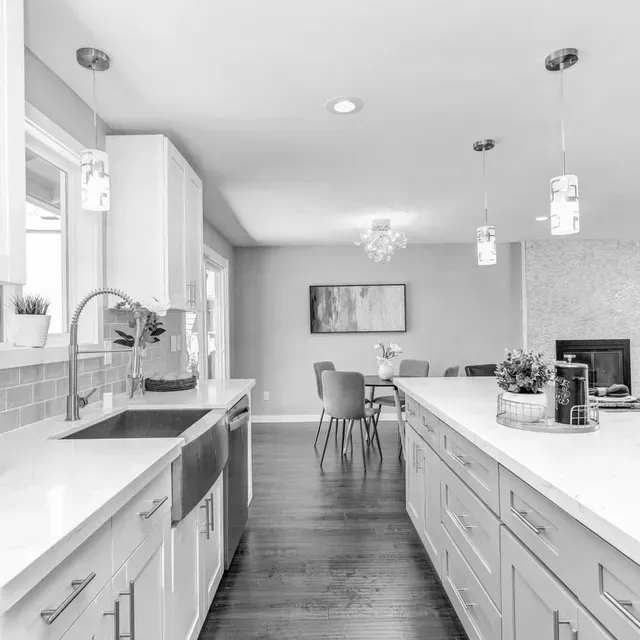 Una foto en blanco y negro de una cocina con gabinetes blancos.
