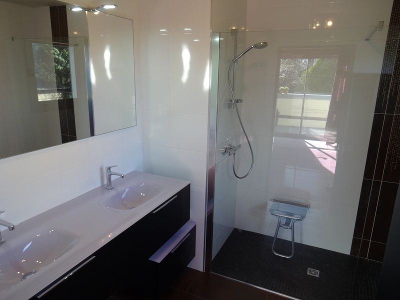Salle de bains moderne avec double vasque, grand miroir et douche vitrée