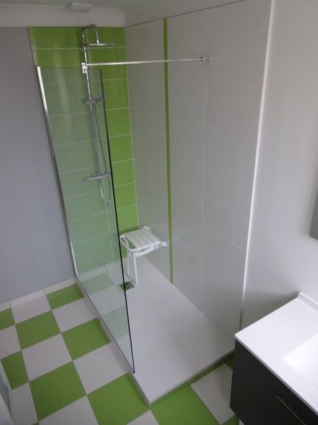 Salle de bains moderne avec douche en verre, carrelage vert citron et sol à damier vert et blanc