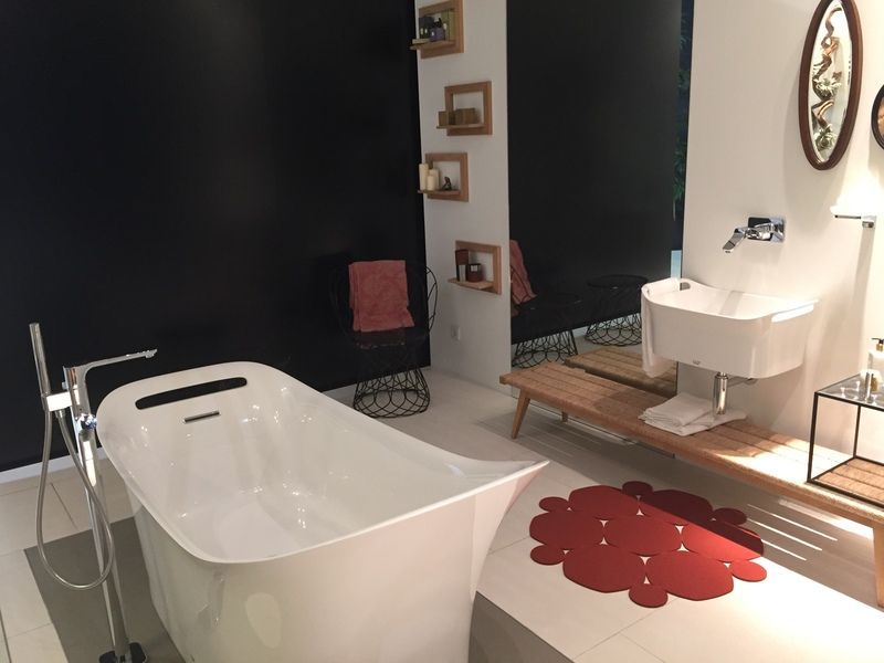 Salle de bains moderne avec baignoire îlot blanche, lavabo sur pied et tapis rouge à fleurs sur parquet
