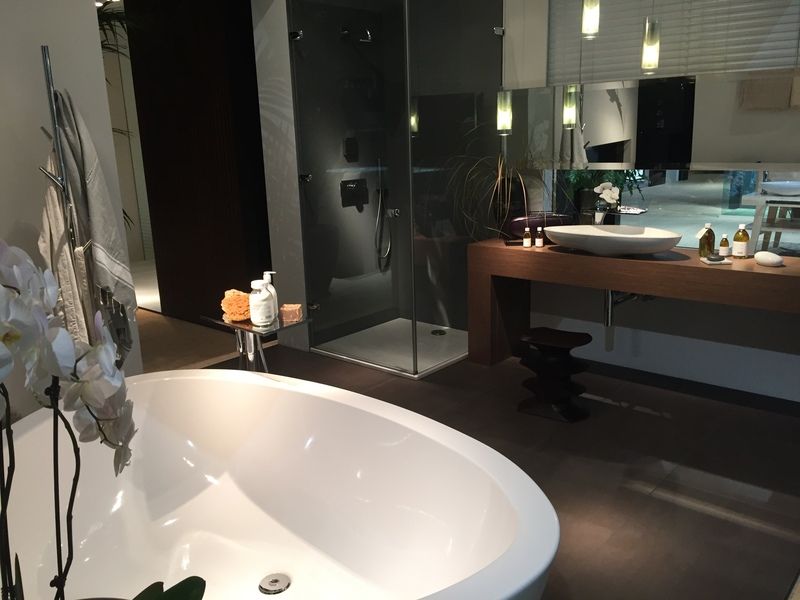 Salle de bains moderne avec baignoire îlot, douche en verre et meuble-lavabo en bois foncé.