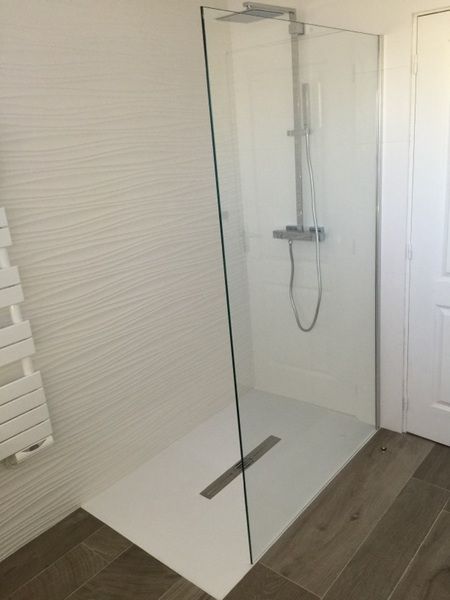 Douche à l'italienne en verre avec robinetterie chromée dans une salle de bains carrelée de blanc