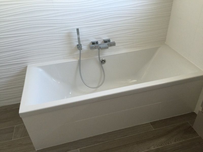 Baignoire blanche moderne avec robinet mural dans une salle de bain minimaliste