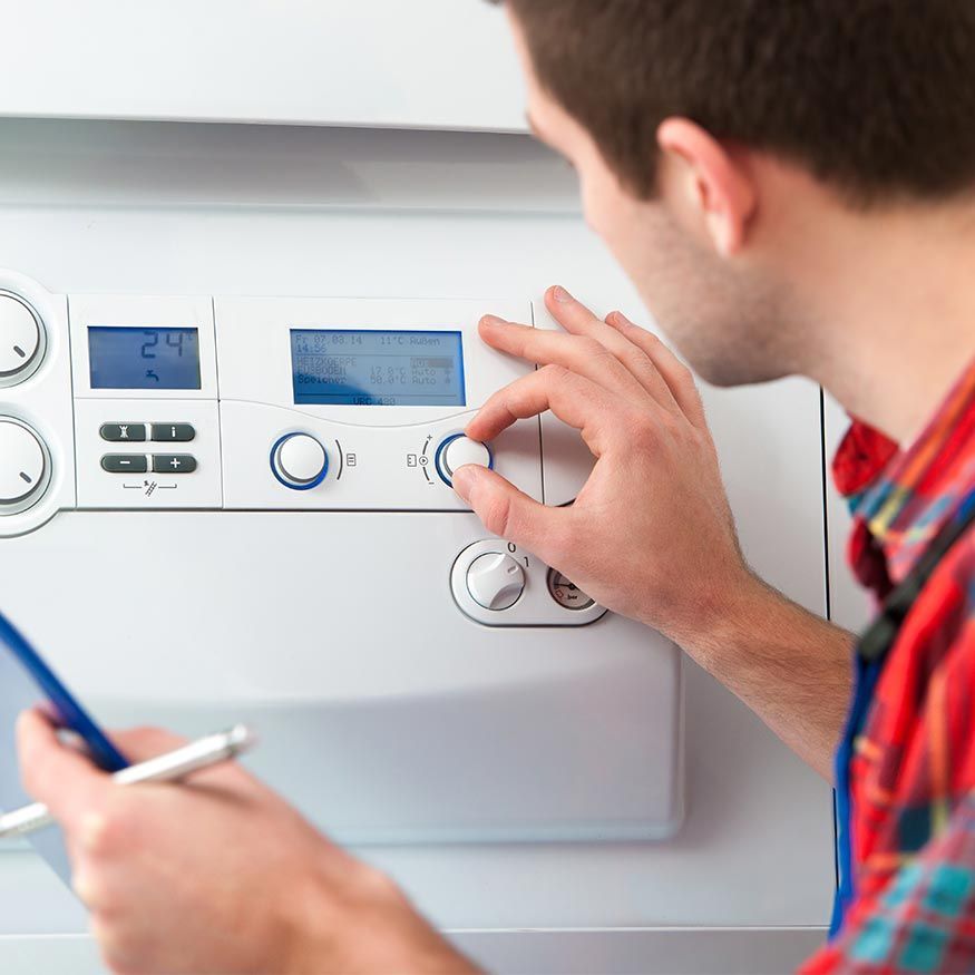 Technicien ajustant un thermostat de chaudière mural avec des outils à la main