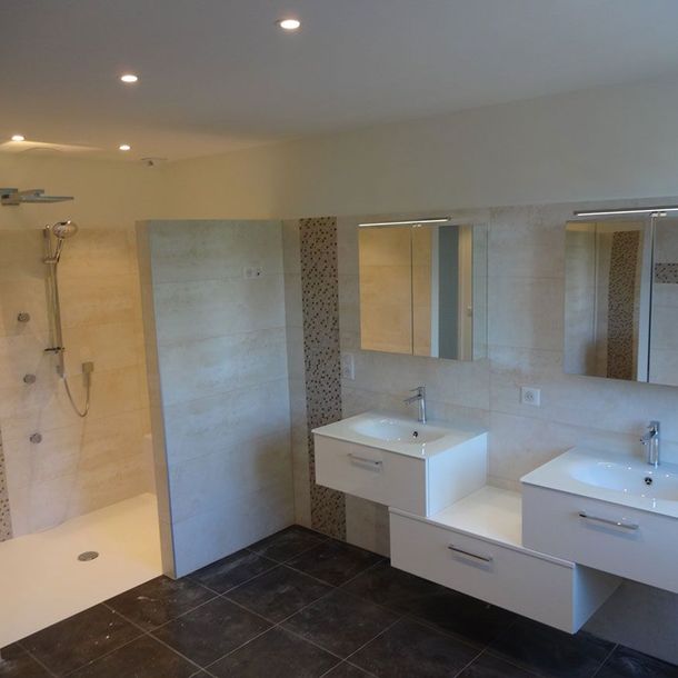 Salle de bains moderne avec douche à l'italienne, meubles vasques suspendus, miroirs et sol carrelé foncé