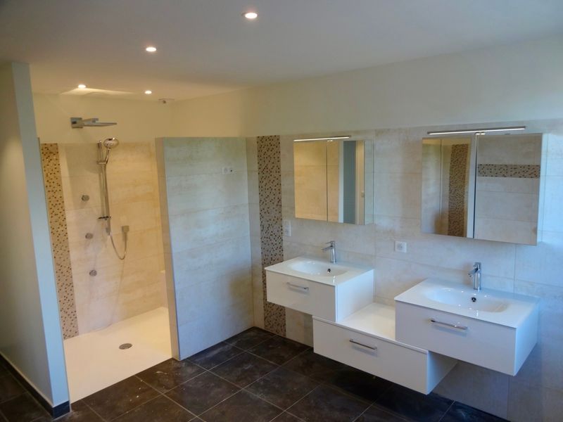 Salle de bains moderne avec douche à l'italienne, double vasque et grands miroirs aux tons neutres.