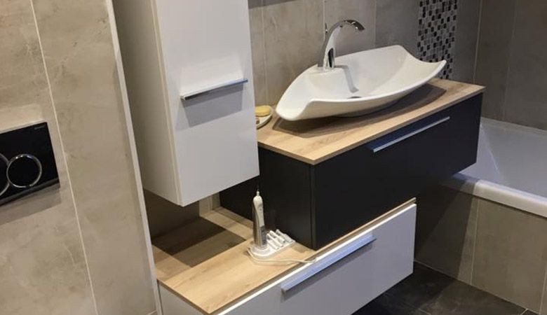 Meuble-lavabo moderne avec vasque, plan de travail en bois et armoire noire à côté d'une baignoire.
