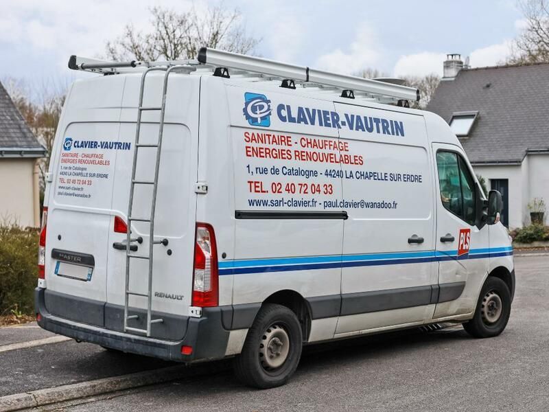 Fourgonnette blanche CLAVIER-AUTIN avec échelle à l'arrière, stationnée dans une rue devant des maisons