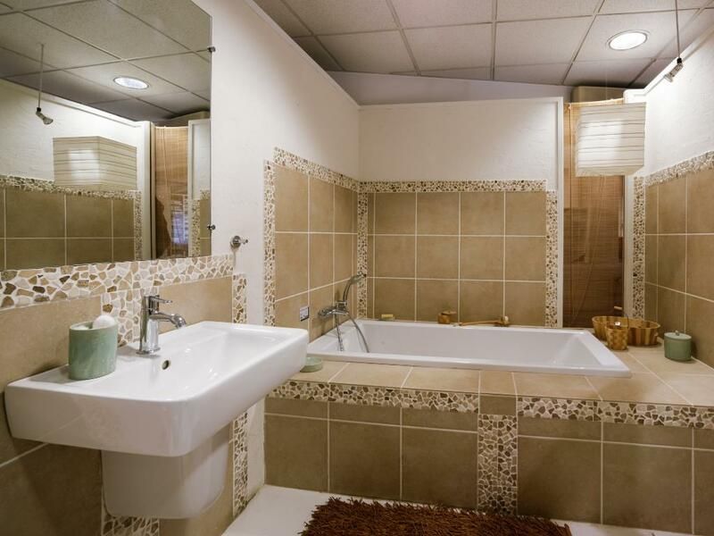 Salle de bain moderne carrelée beige avec lavabo, baignoire, miroir et appliques murales