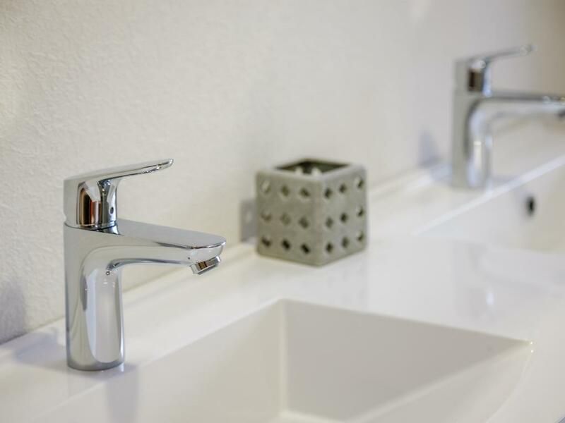 Robinet de salle de bain chromé moderne au-dessus d'un lavabo blanc avec un porte-savon en arrière-plan