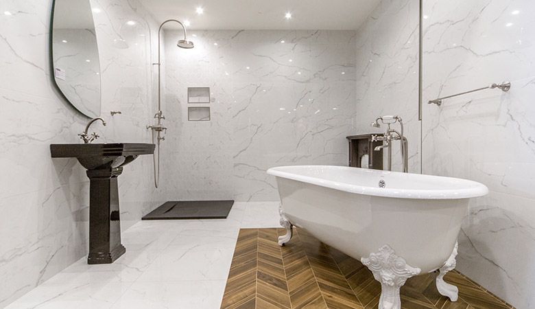 Salle de bains moderne blanche avec baignoire îlot, lavabo sur pied, douche en verre et tapis de sol en bois