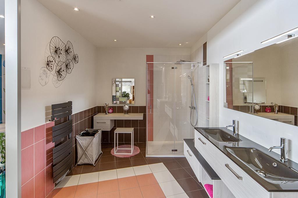 Salle de bain moderne avec double vasque, grand miroir, douche à l'italienne et mur d'accent rose