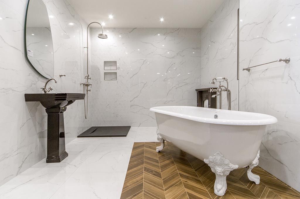 Salle de bains moderne blanche avec baignoire îlot, lavabo noir et grand miroir sur un tapis à chevrons