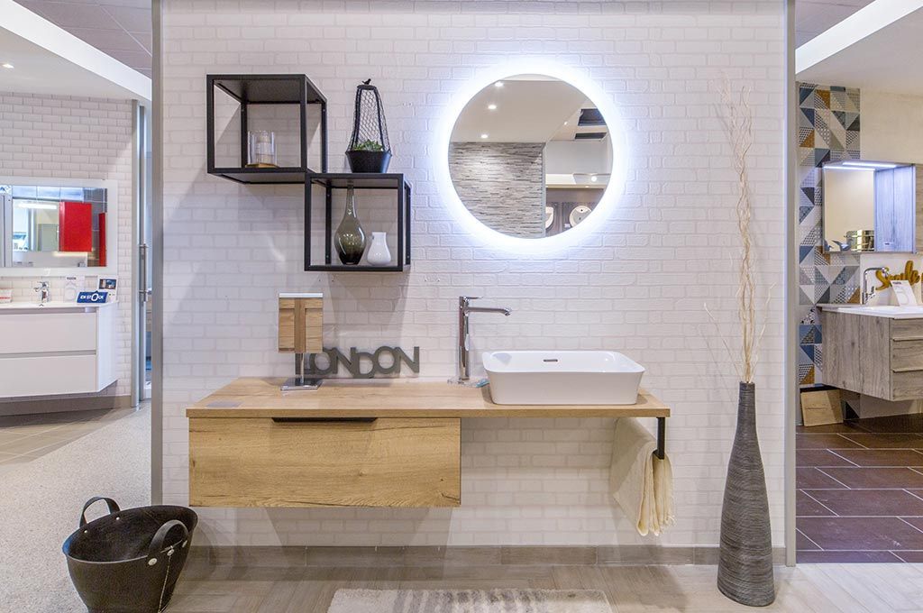 Meuble-lavabo moderne avec miroir rond, meuble vasque suspendu en bois, étagères et mur carrelé blanc.