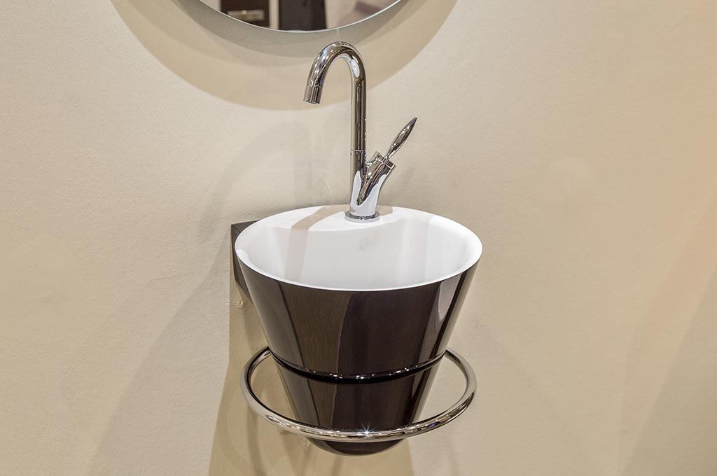 Lavabo mural blanc avec robinet chromé et garniture marron foncé dans une salle de bains.