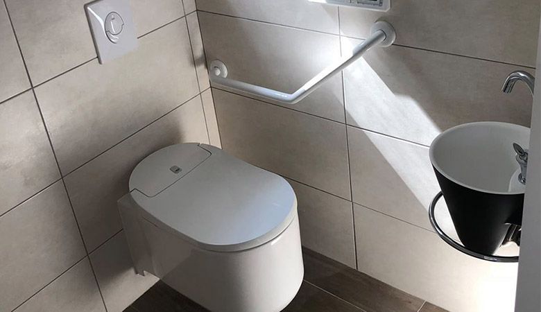Main utilisant un chalumeau pour chauffer un tube métallique dans un atelier, avec une flamme vive et des étincelles.