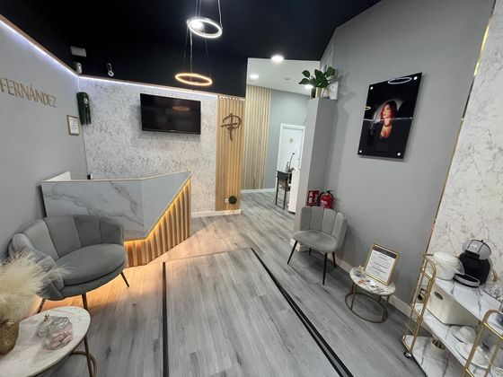 Sala de estar beige con sofá seccional, mesa auxiliar, lámpara, alfombra y ventana con cortinas.