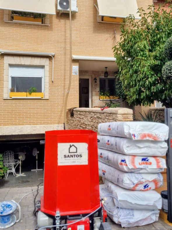 Cocina moderna y luminosa con gabinetes blancos, encimeras de cuarzo y una gran isla. Pisos de madera oscura y una chimenea al fondo.