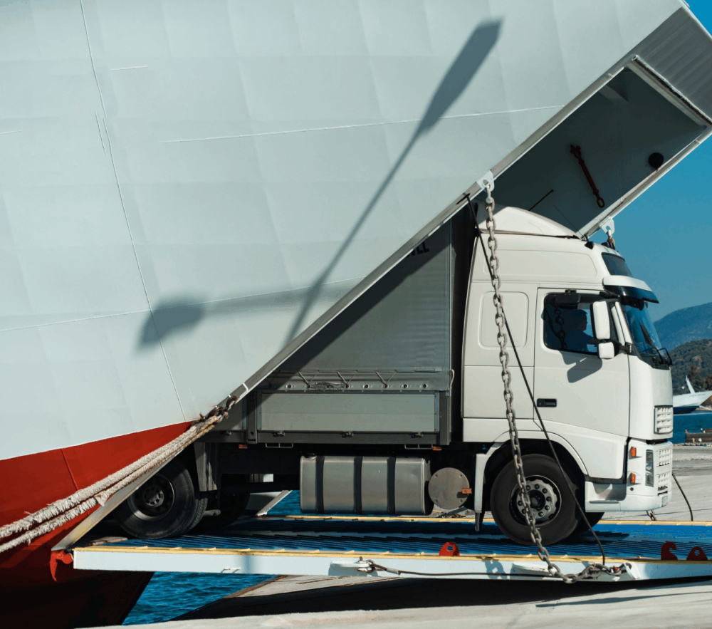 Un camión blanco está estacionado al lado de un barco grande.