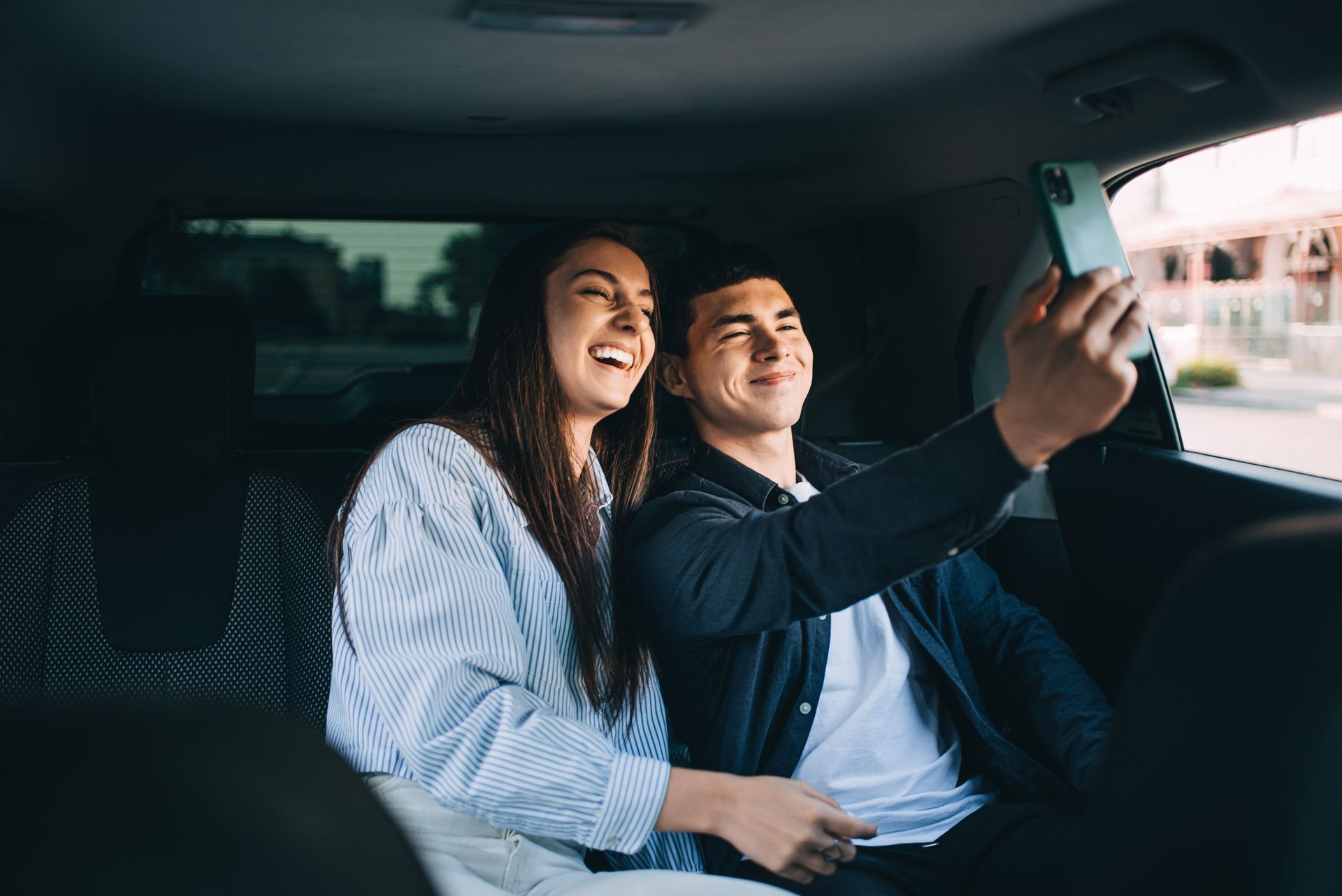 Deux personnes sourient dans une voiture en prenant un selfie ensemble