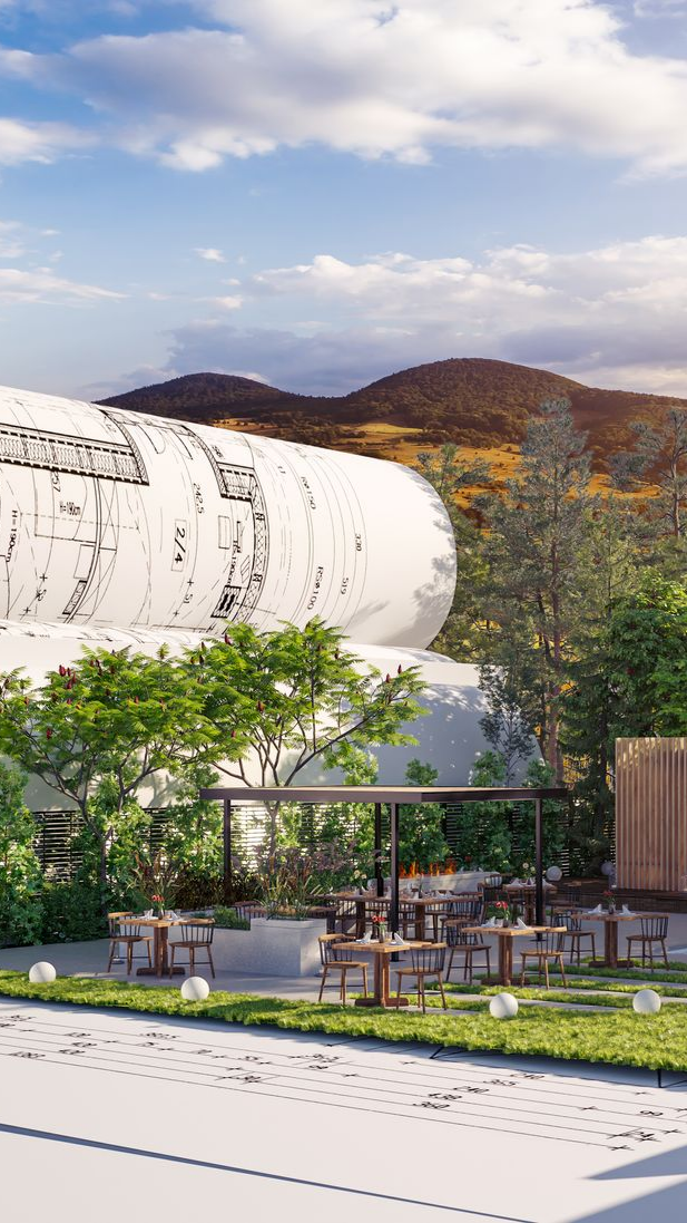 Café en plein air avec tables, chaises et arbres ; grande structure blanche en arrière-plan, montagnes sous ciel bleu.