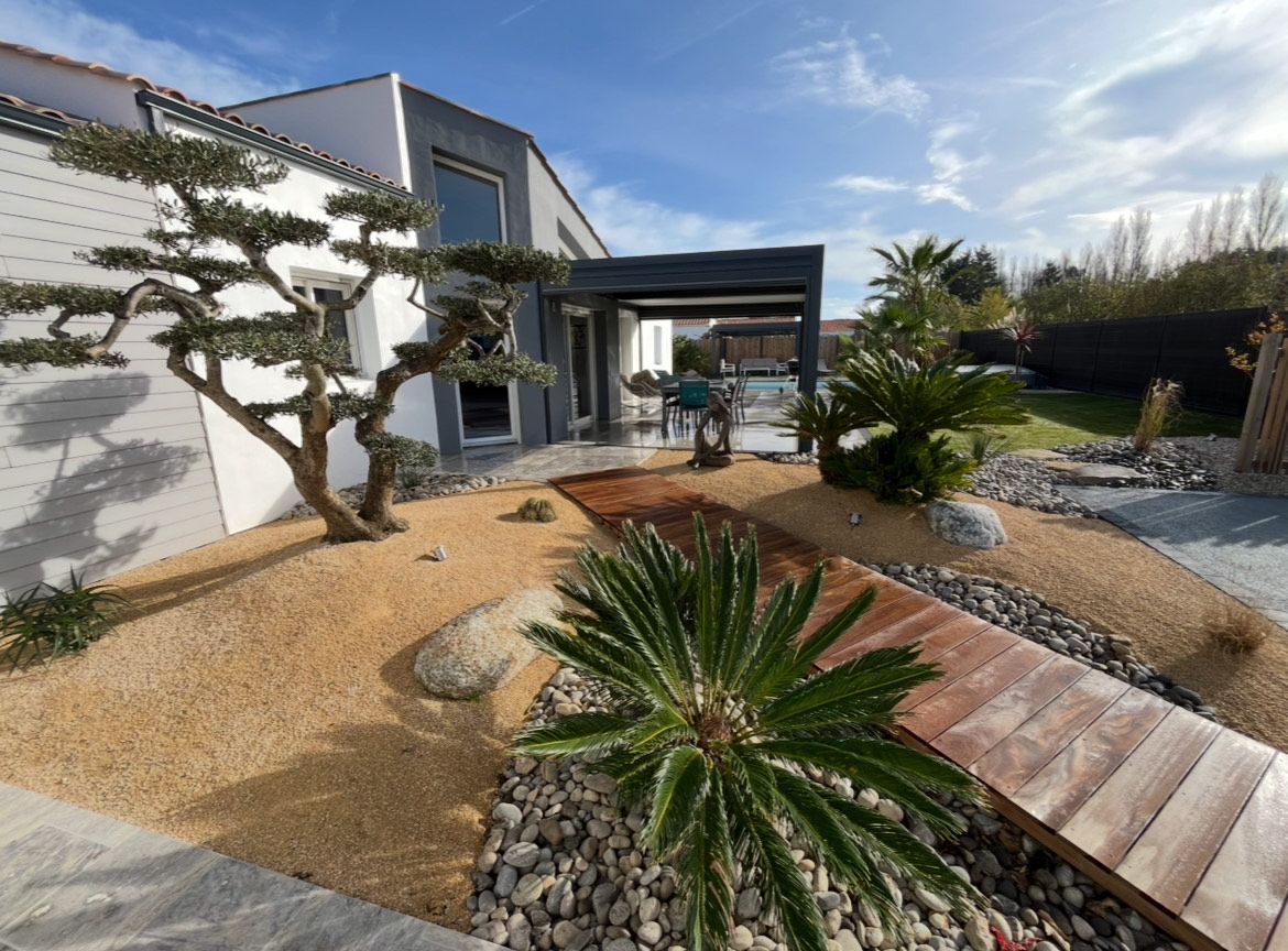 Parterre de jardin avec grand arbre à feuilles persistantes, fleurs violettes et roses et buissons verts.