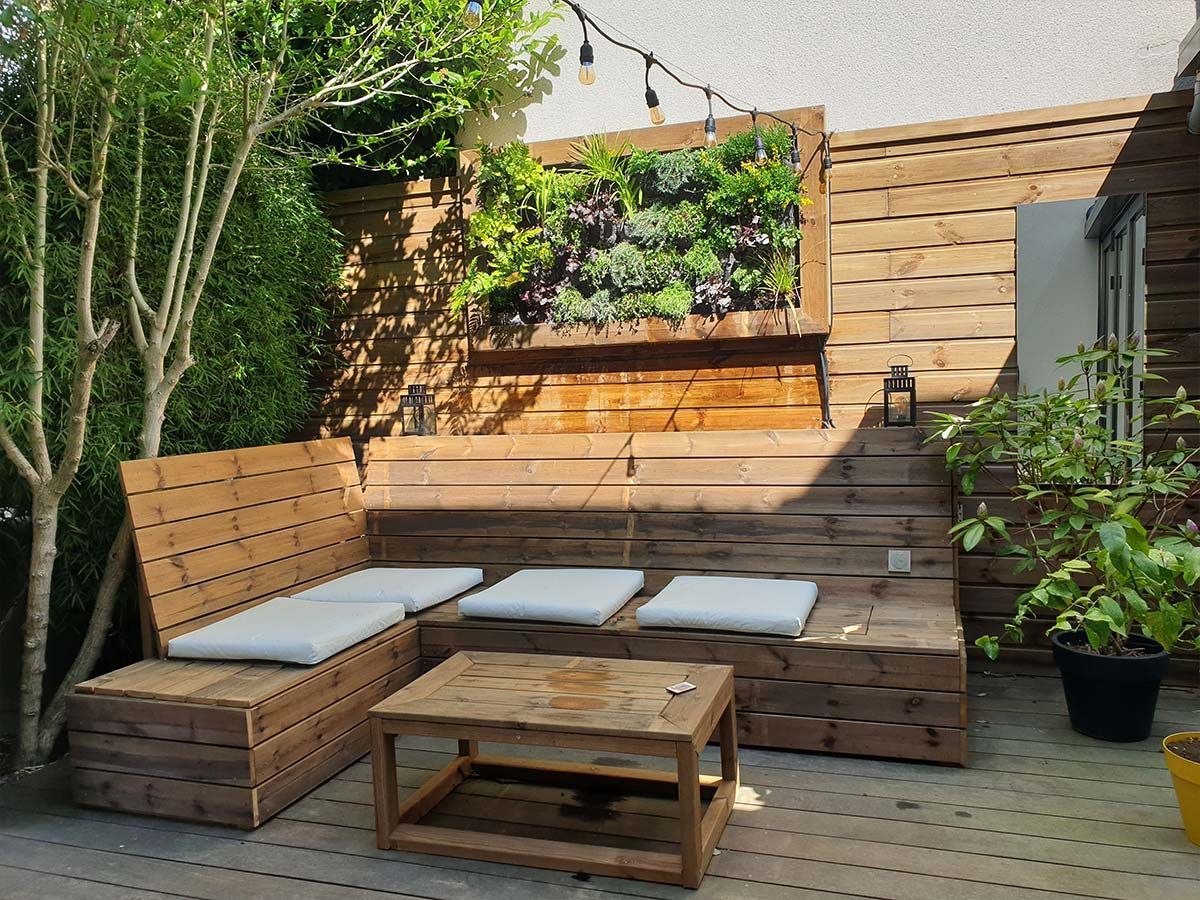 Salon de jardin sur une terrasse extérieure avec un mur végétal
