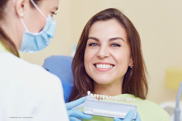 Frau sitzt im Behandlungsstuhl beim Zahnarzt und lächelt