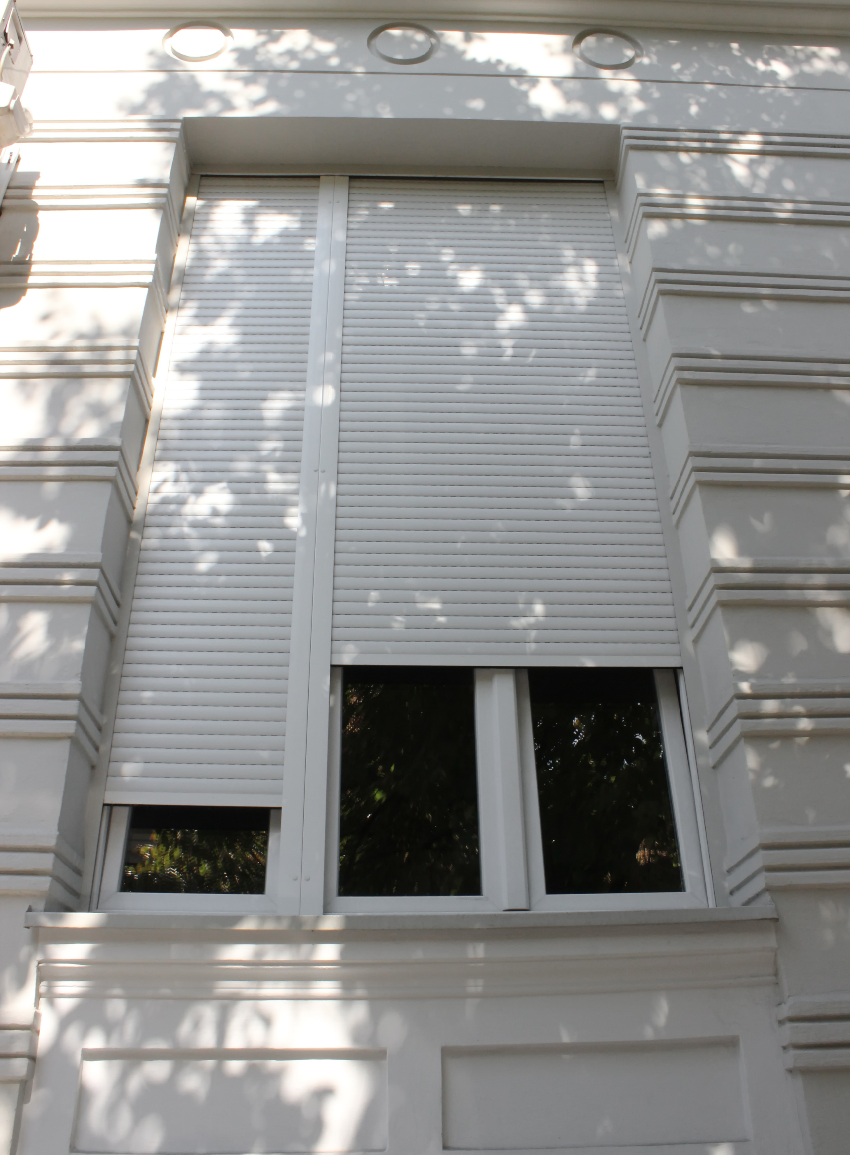 Un bâtiment blanc avec une fenêtre avec un volet dessus