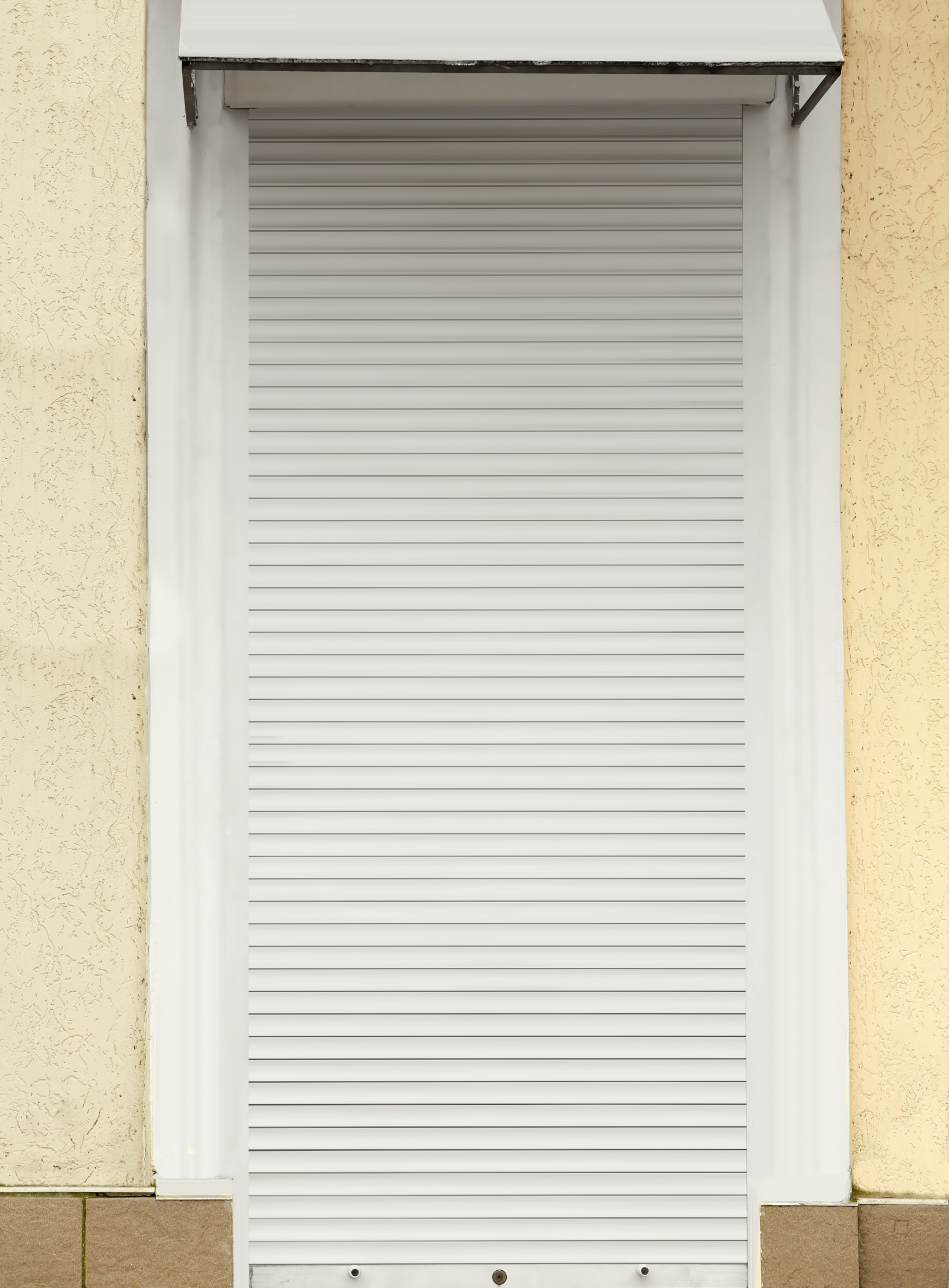 Un volet roulant blanc sur une fenêtre sur le côté d'un bâtiment.