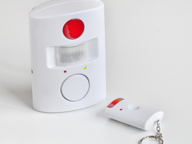 Une alarme blanche avec un bouton rouge et une télécommande