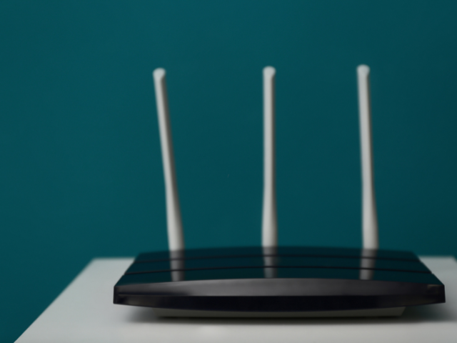 Un routeur avec trois antennes est posé sur une table.