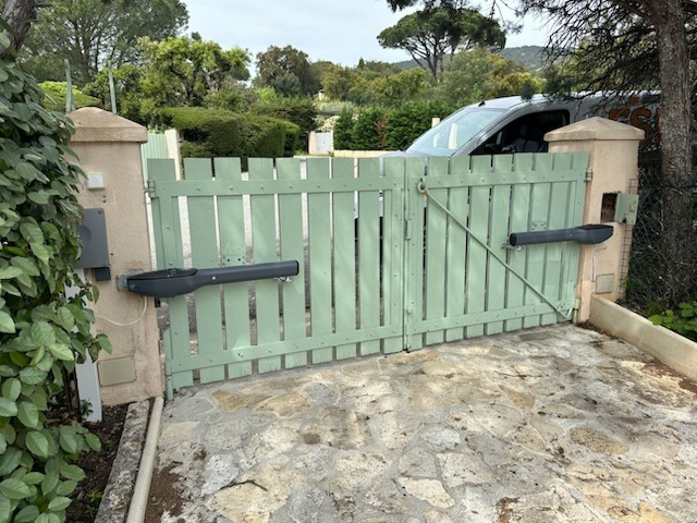 Un portail en bois vert avec une voiture garée derrière.