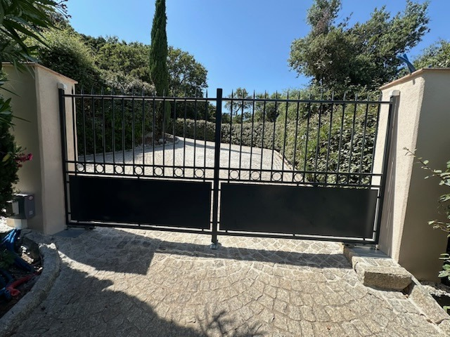 Une porte noire est ouverte sur une allée avec des arbres en arrière-plan