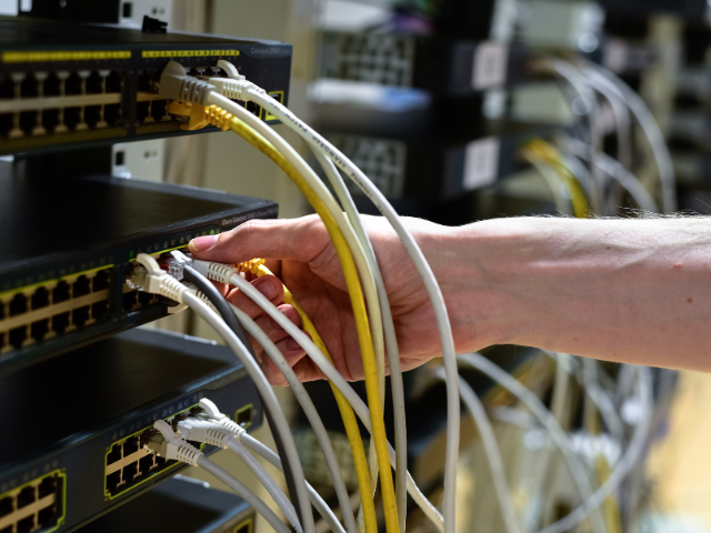Une personne branche un tas de fils sur un serveur.