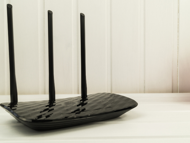 Un routeur noir est posé sur une table blanche.