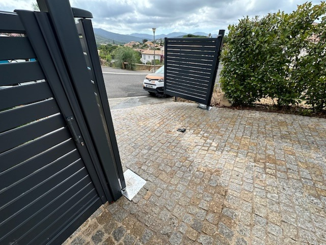 Une voiture est garée devant un portail qui est ouvert.