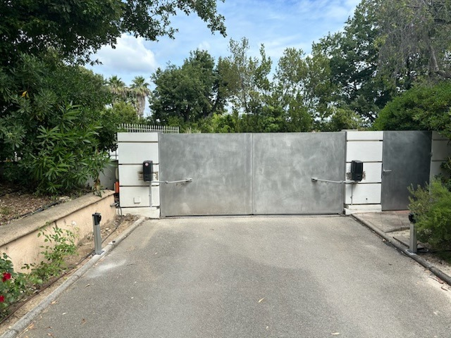 Une allée fermée avec un portail en métal et des arbres en arrière-plan