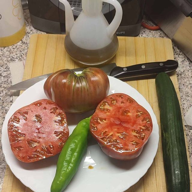 Un plato de tomates y pimientos verdes en una tabla de cortar